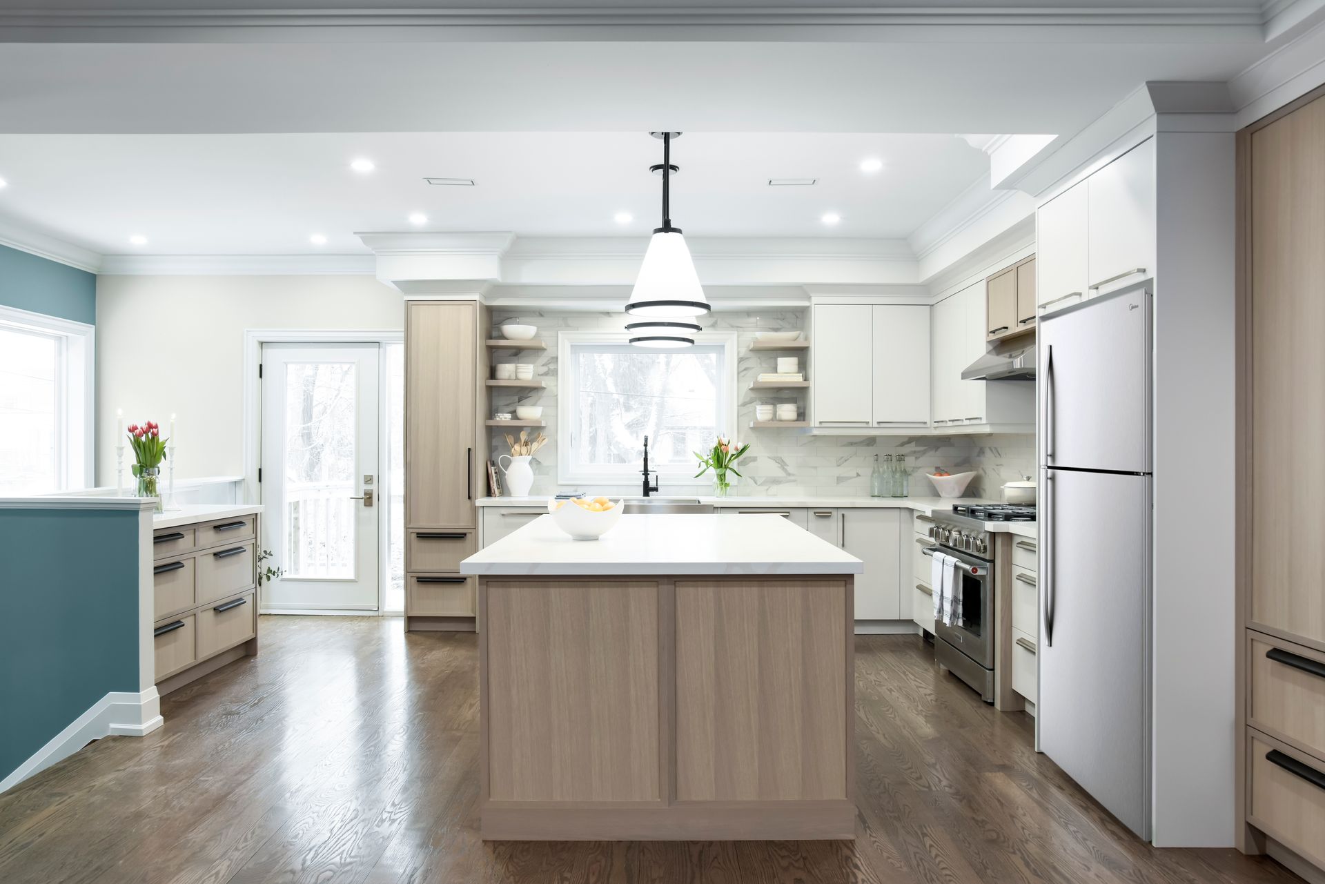 Spacious modern kitchen with island, light wood cabinetry, stainless appliances, and hardwood floors.