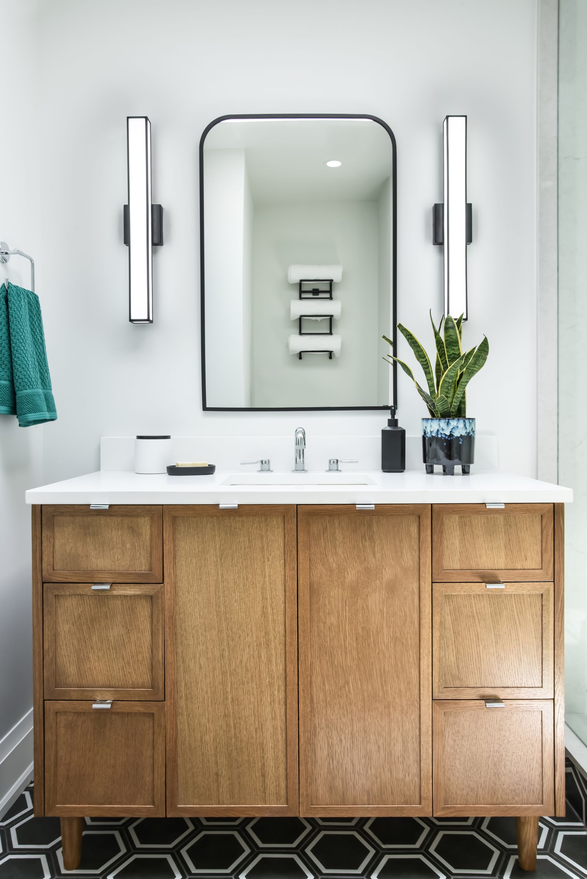 Bathroom with wooden vanity, large mirror, and black and white hexagon floor tiles.