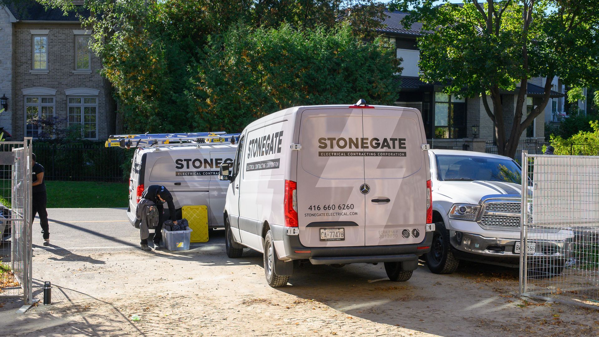 Two StoneGate vans and a white SUV parked in a driveway in front of a house.
