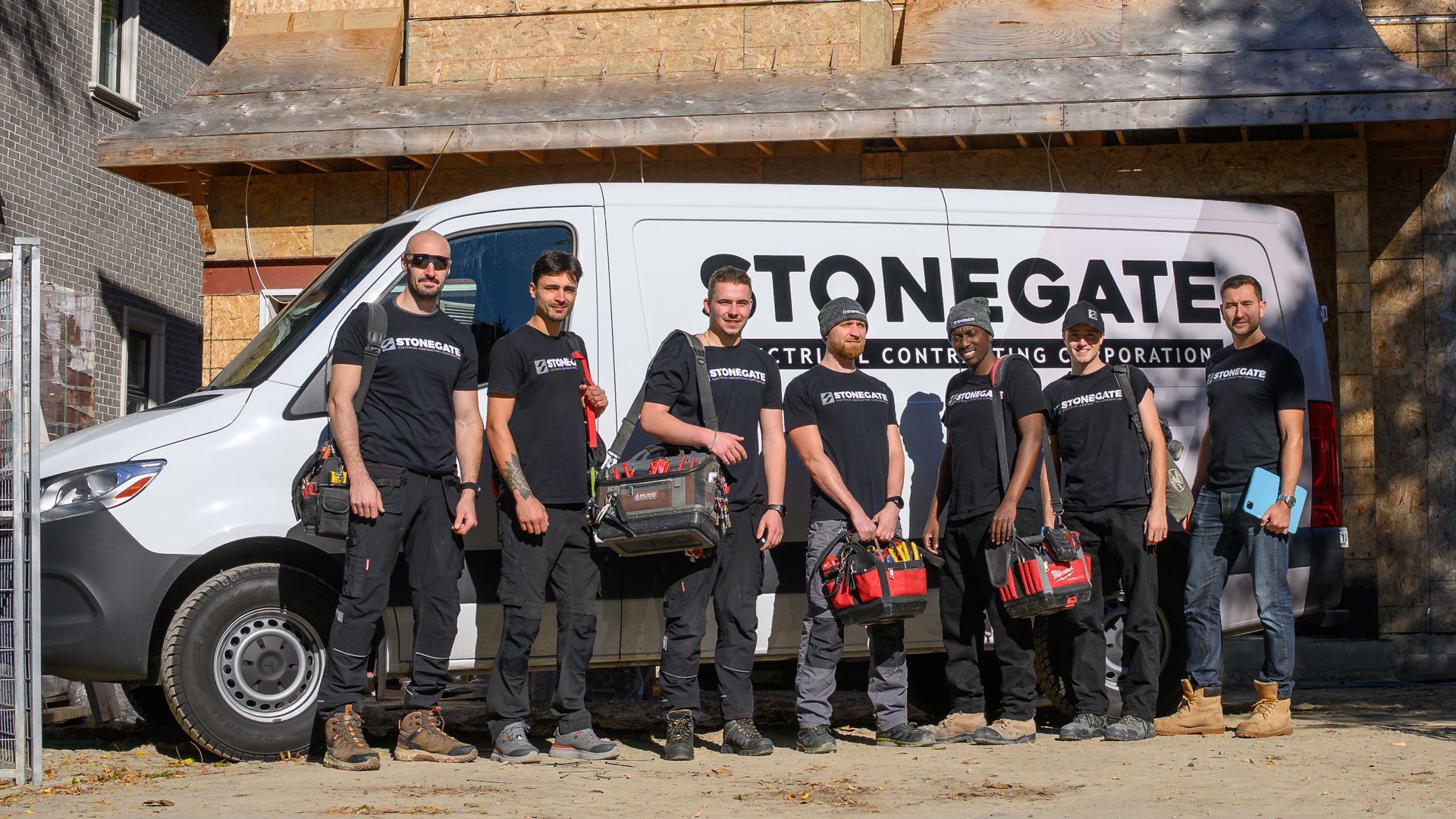 A group of construction workers in front of their company van, labeled Stonegate.