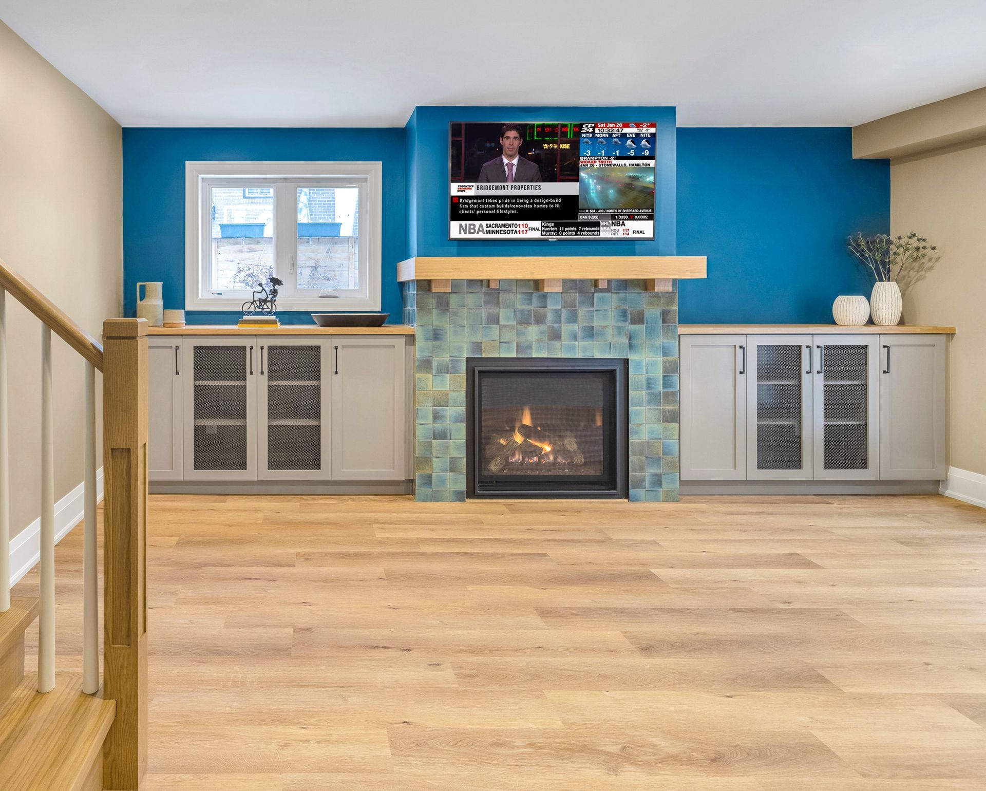 Living room with fireplace, blue accent wall, TV, and light wood flooring.