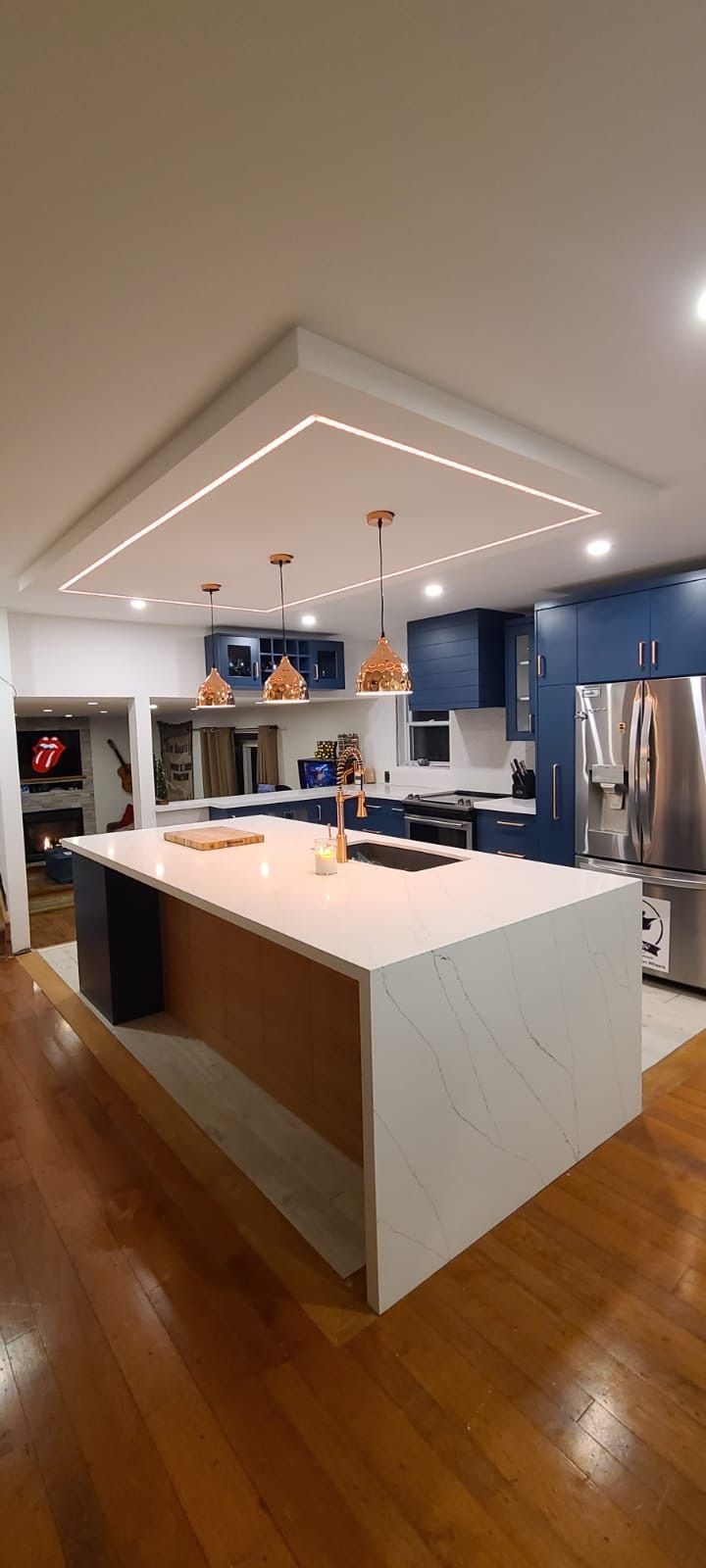 Modern kitchen with blue cabinets, white countertops, and copper pendant lights.