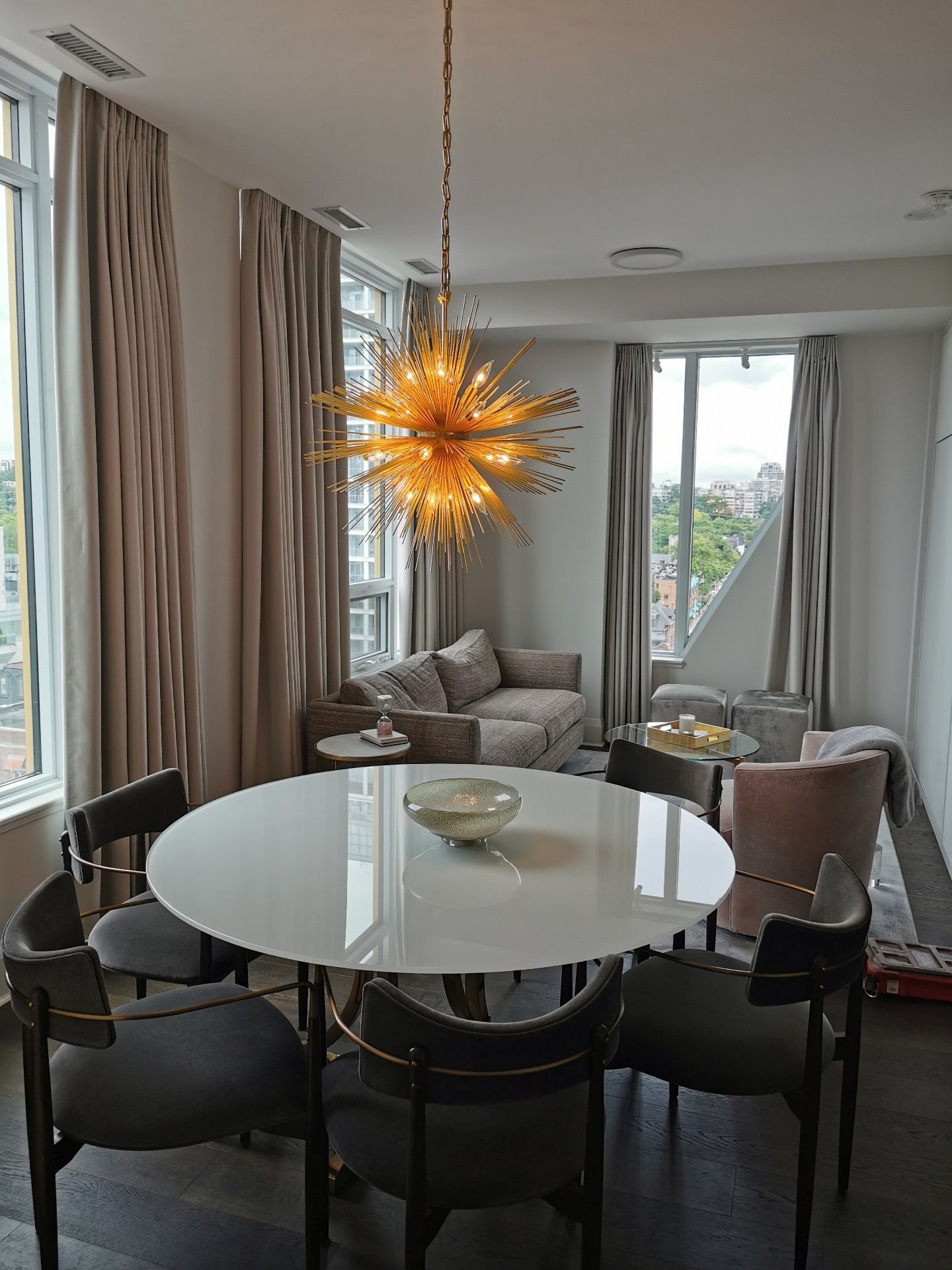 Dining room with a white round table, chairs, and a gold sputnik chandelier.