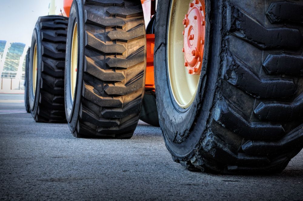 Close-up of orange heavy machinery tires on asphalt. — Jakes Tyres in South Murwillumbah, NSW