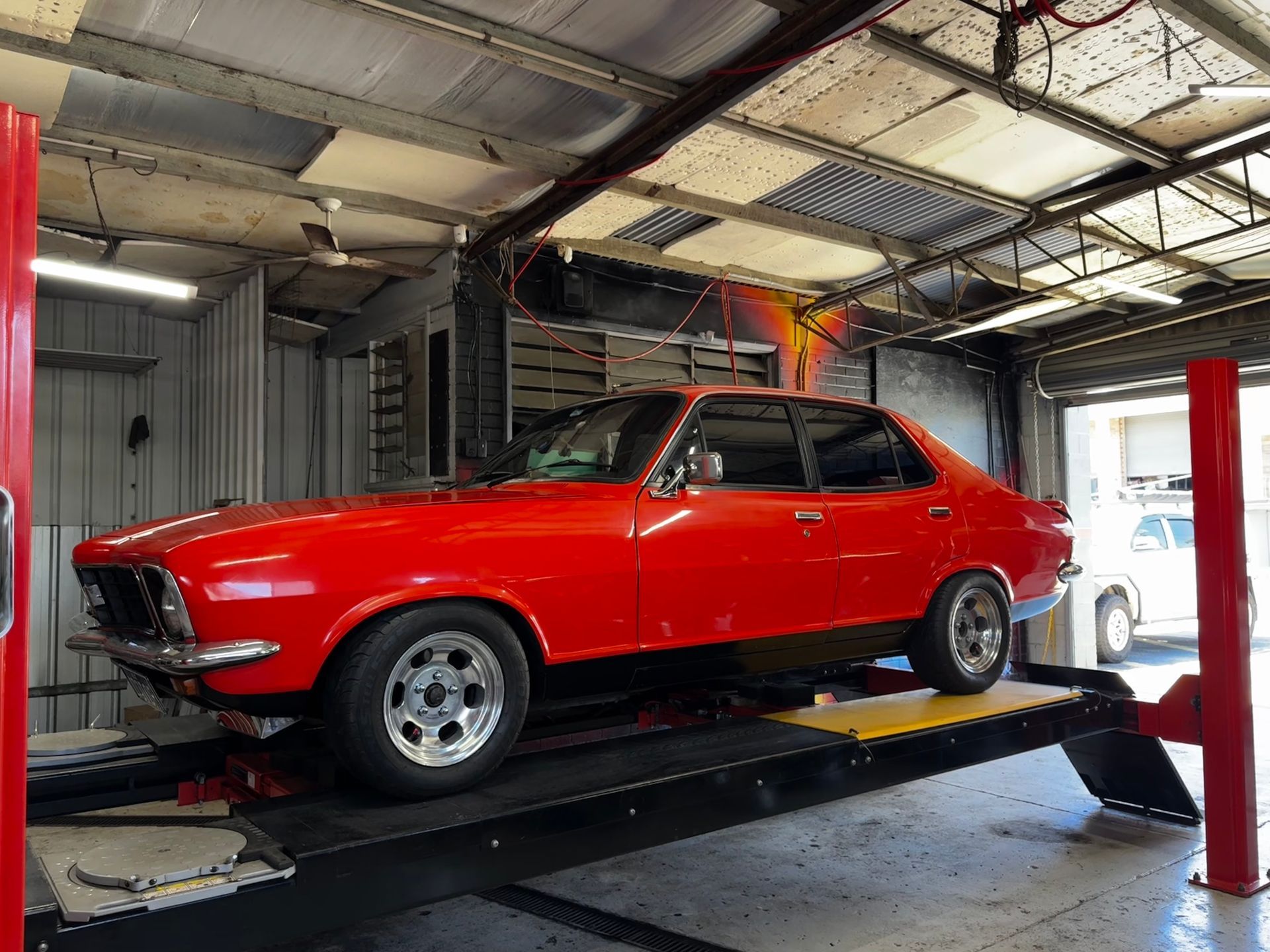 A Red Vintage Car Raised on A Lift Inside a Garage — Jakes Tyres in South Murwillumbah, NSW