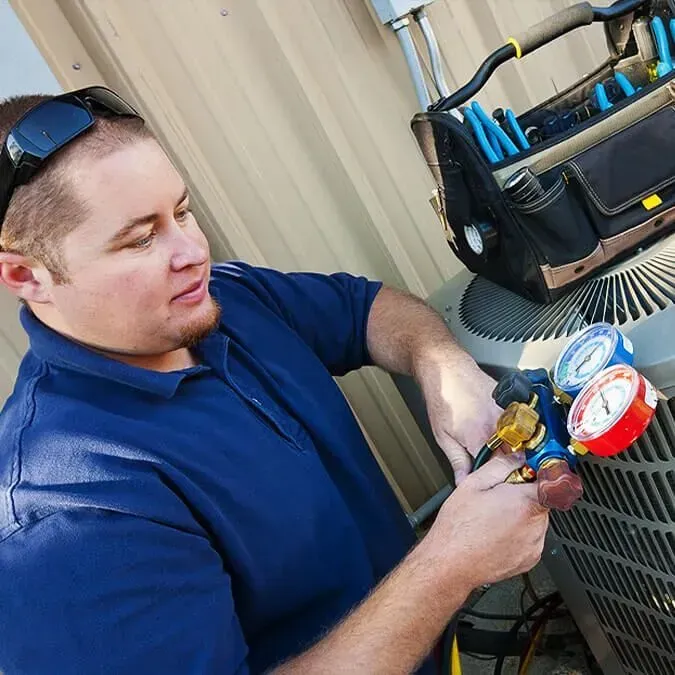 A man is fixing an air conditioner with a wrench.