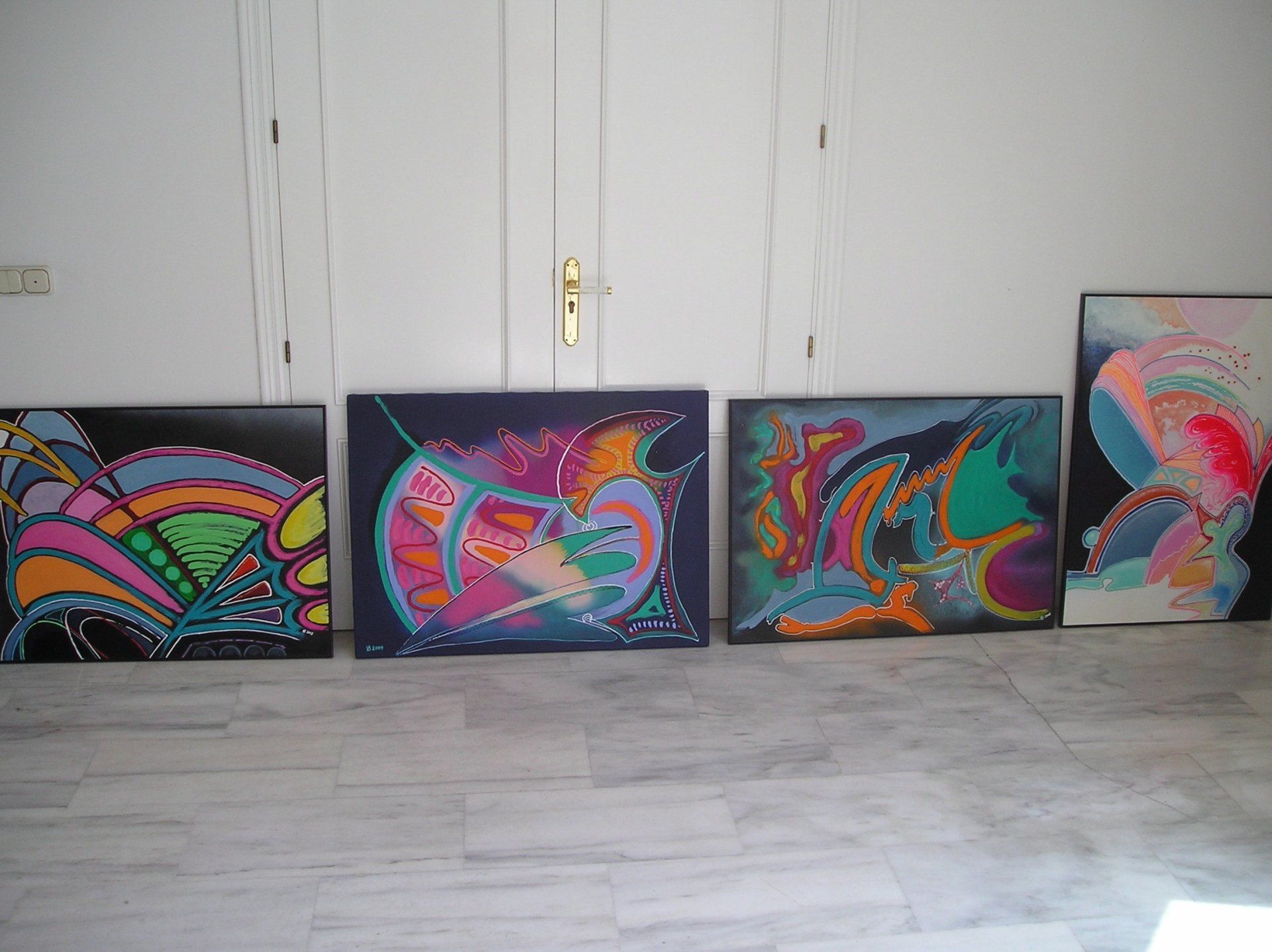 Vier bunte Gemälde sind in einem Raum aufgereiht