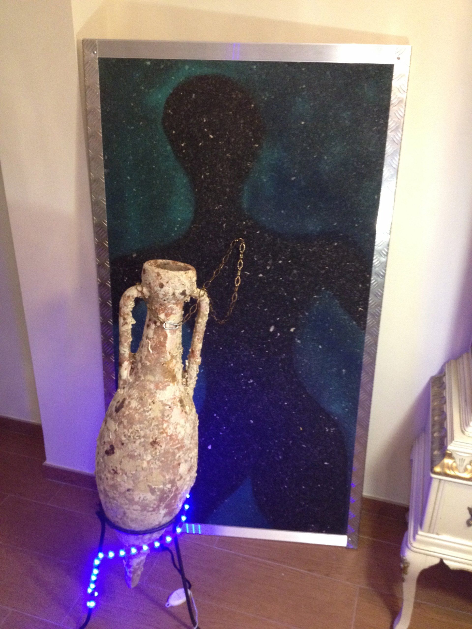 Eine Vase steht auf einem Ständer vor einem Gemälde