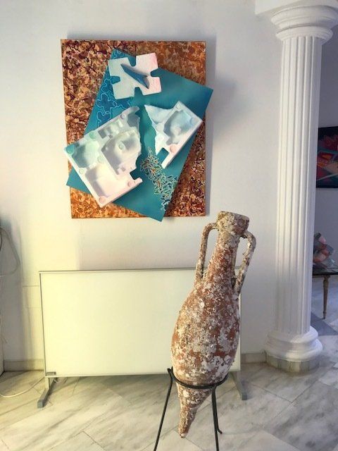 Eine große Vase steht vor einem Gemälde an der Wand