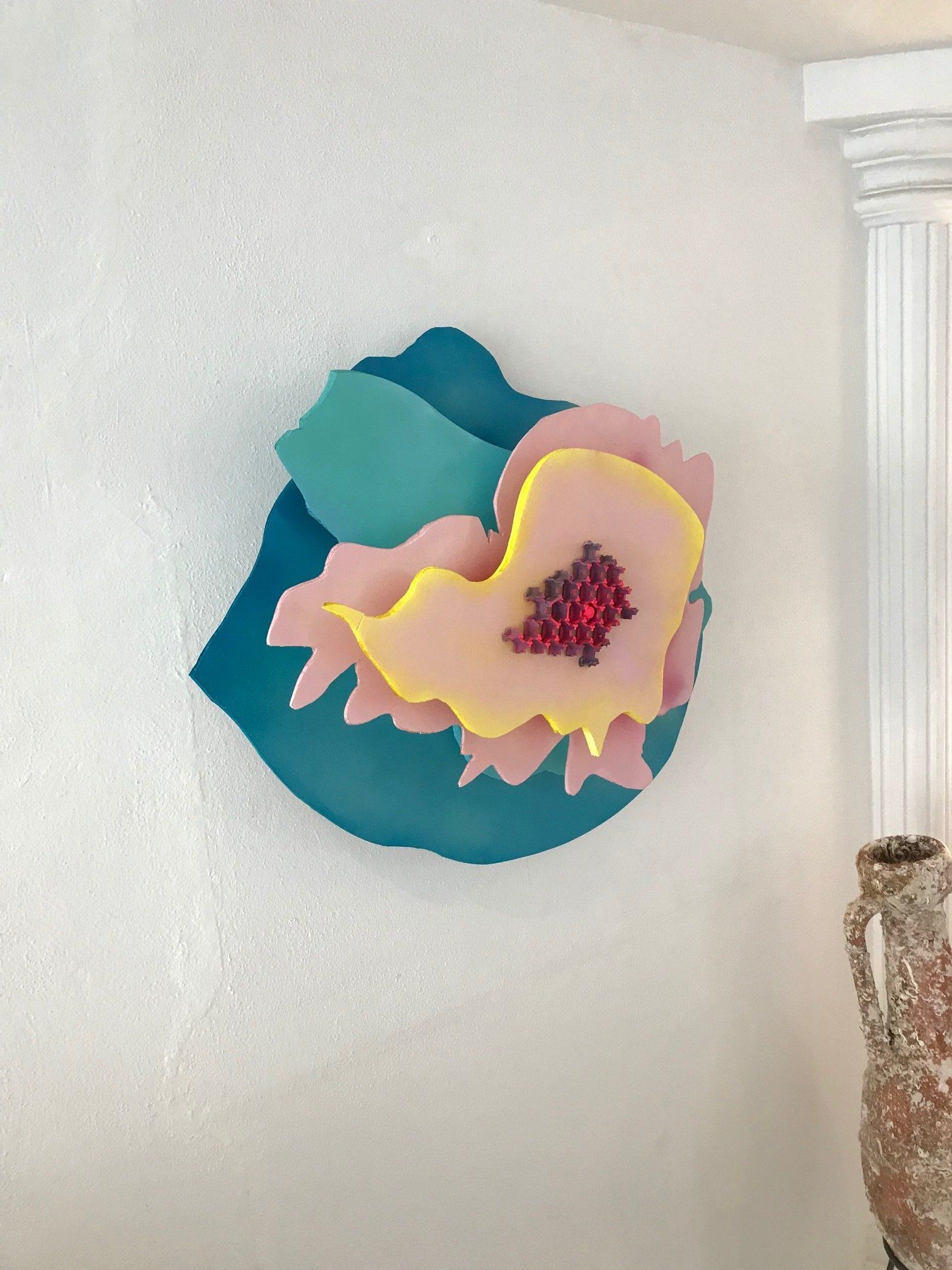 Ein Gemälde einer Blume an einer Wand neben einer Vase