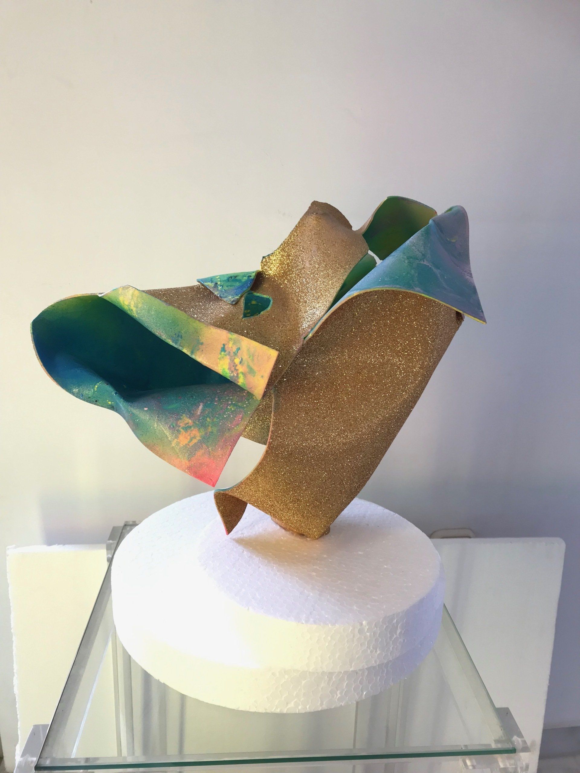 Eine farbenfrohe Skulptur sitzt auf einem Glastisch