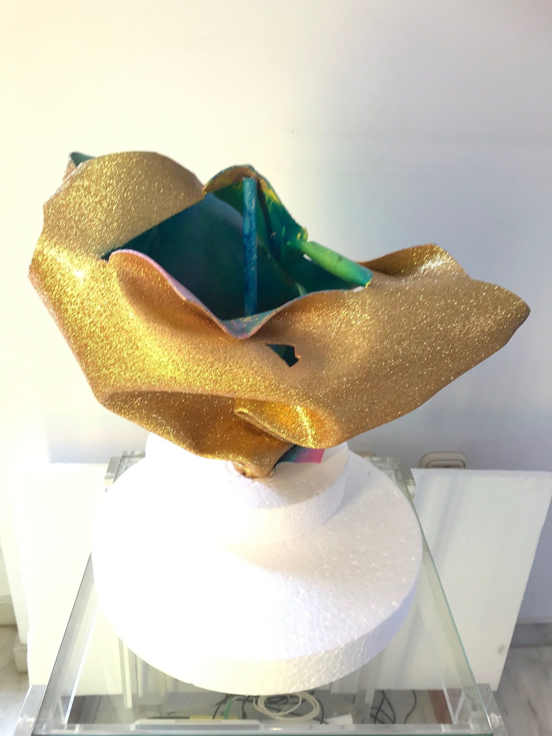 Eine Skulptur einer Blume aus Gold und grünem Glitter