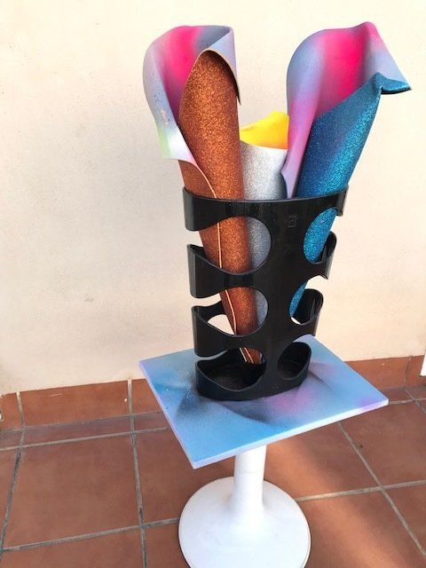 Eine Vase mit einem Bündel verschiedenfarbiger Papiere darin