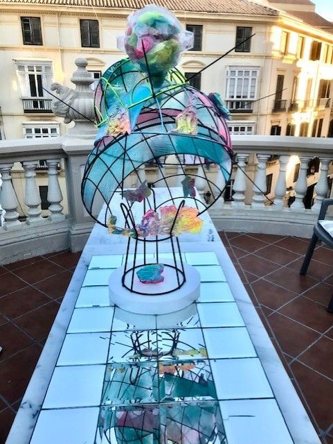 Eine Skulptur auf einem Balkon mit einem Gebäude im Hintergrund