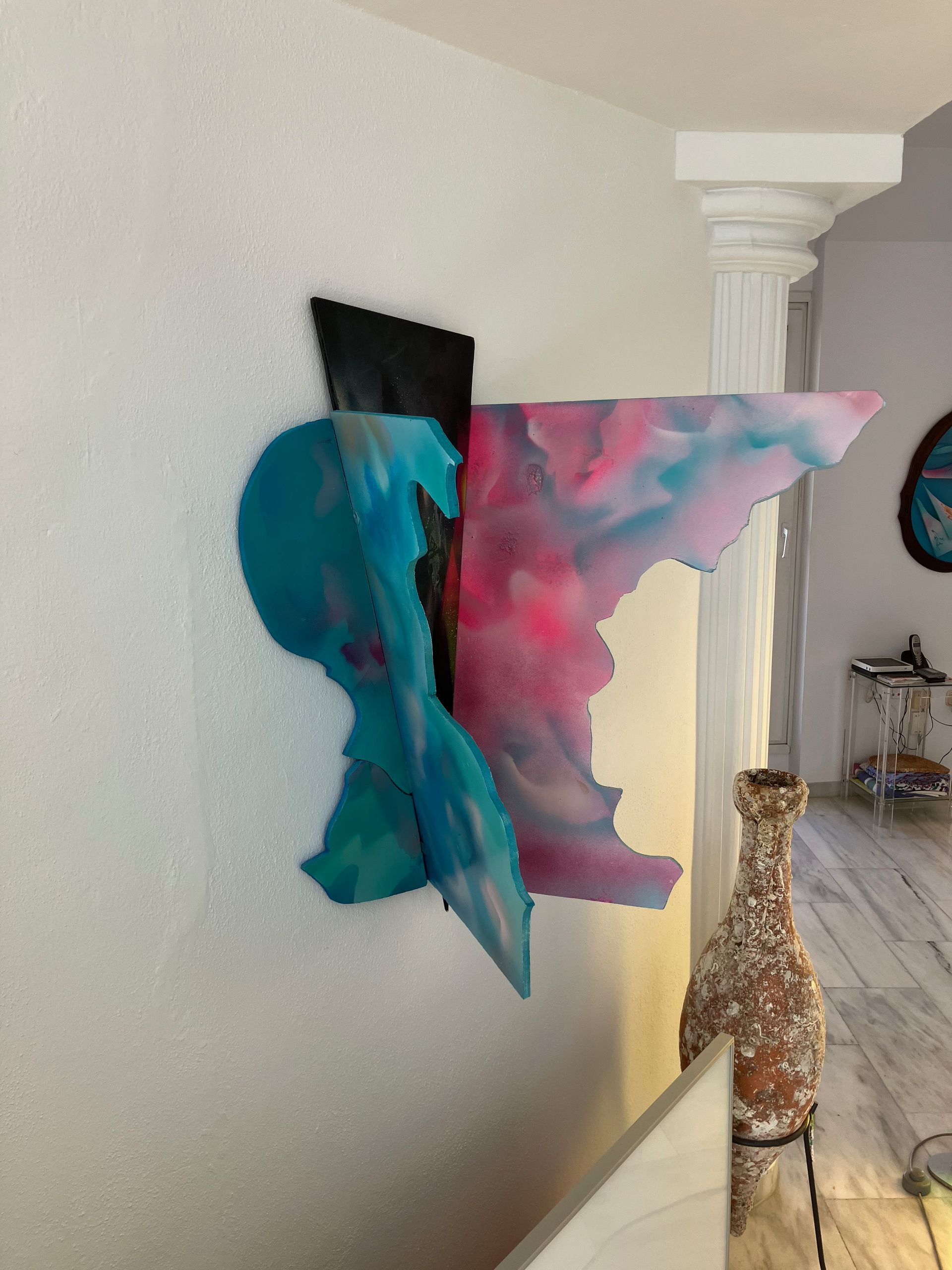 Ein Gemälde hängt an einer Wand neben einer Vase