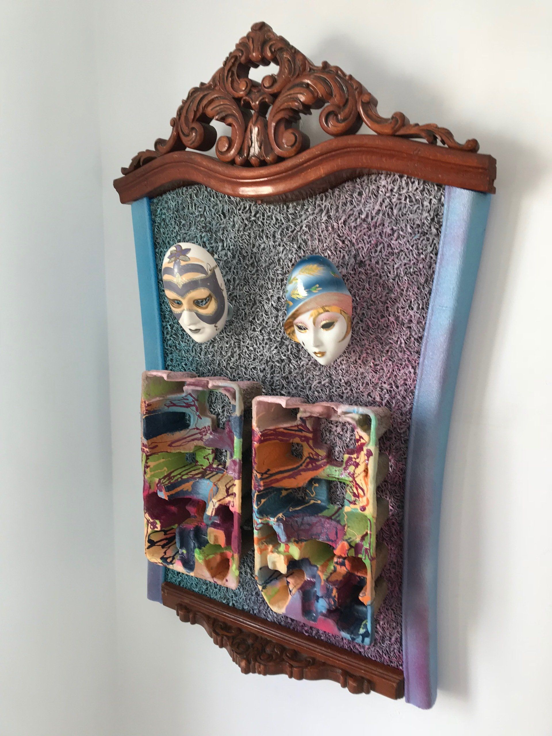 Ein Spiegel mit zwei Masken darauf, der an einer Wand hängt