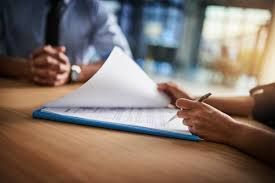 A man and a woman are shaking hands in an office.