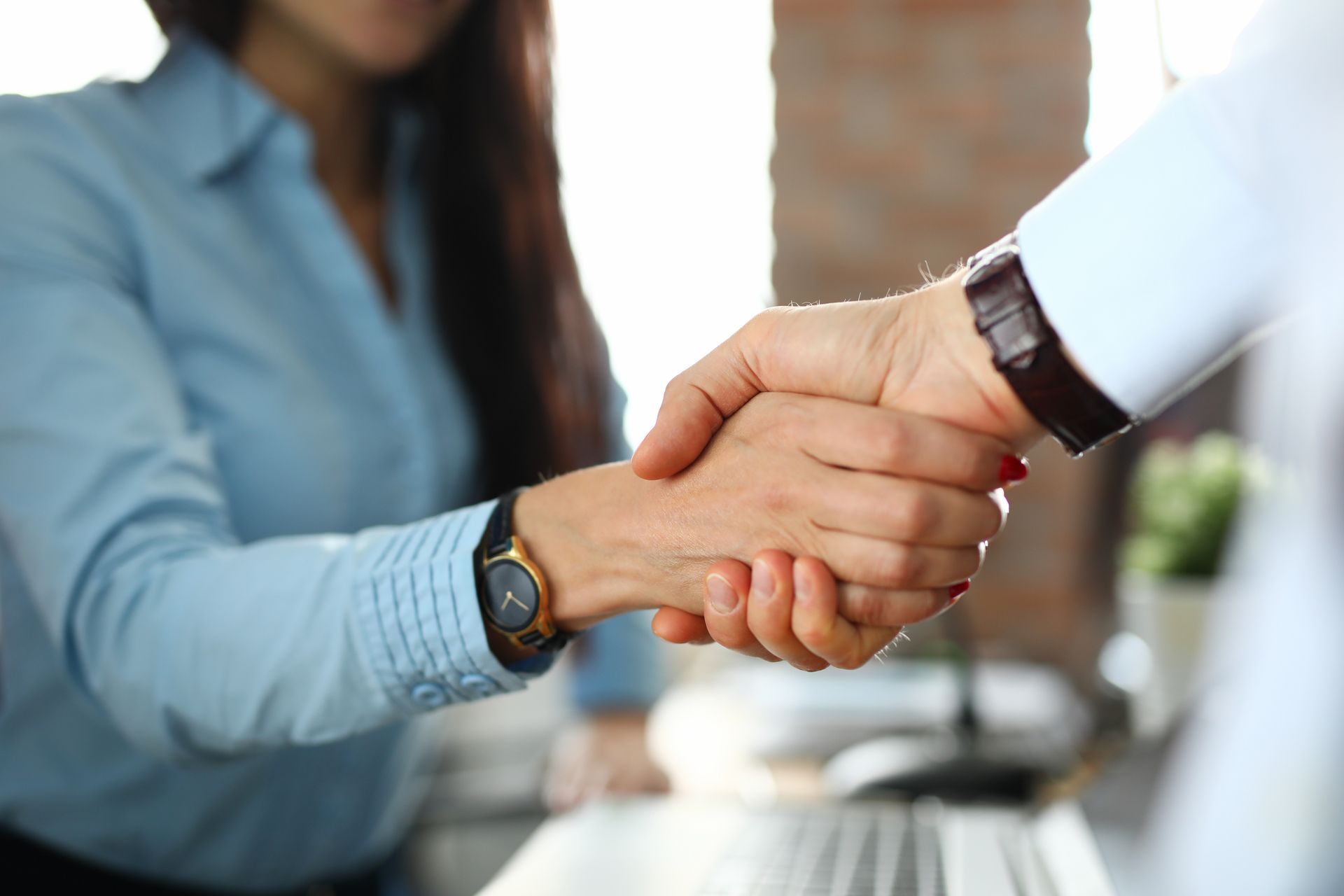 A man and a woman are shaking hands in an office.