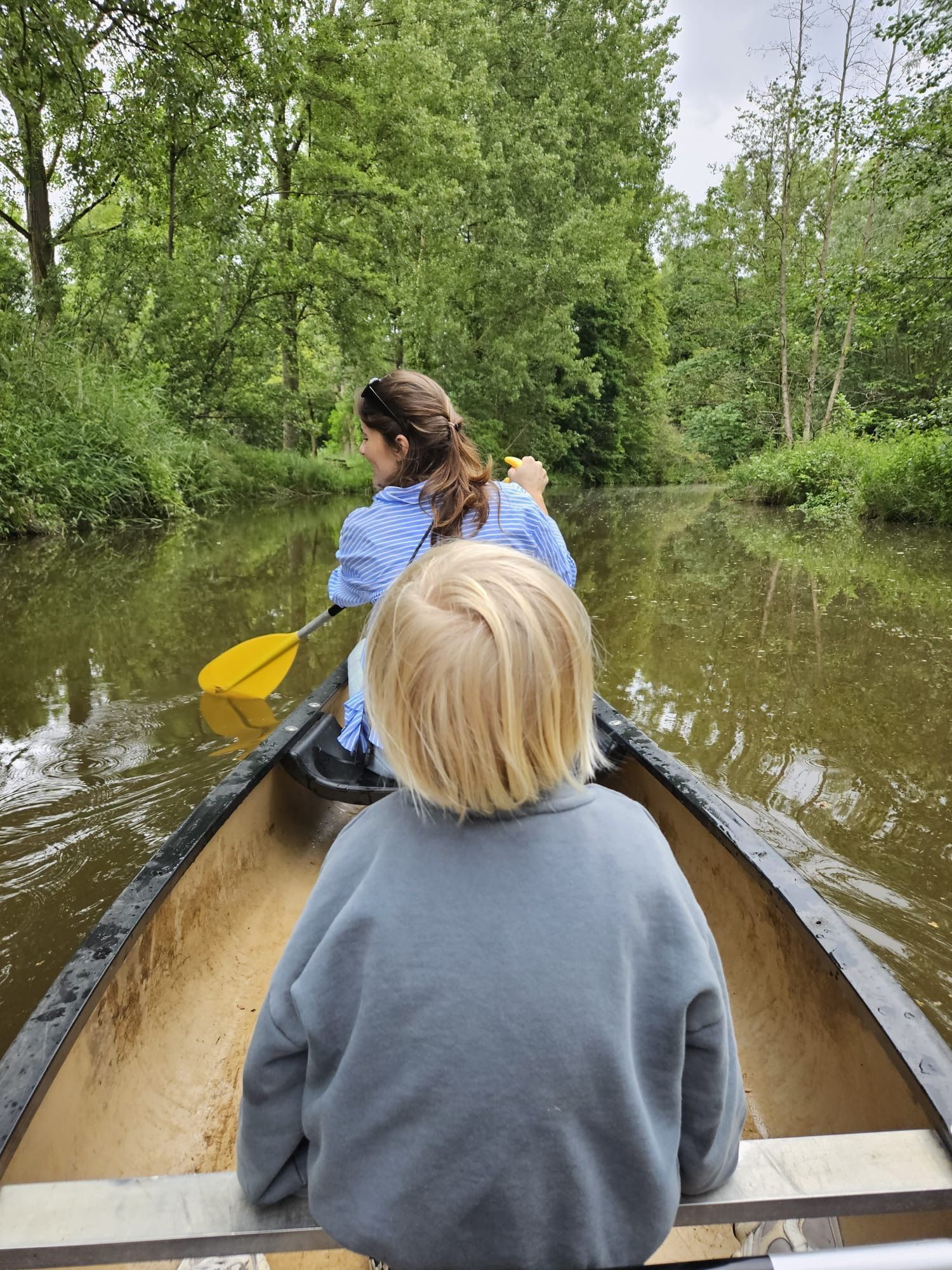 Een boot drijft op de rivier met een brug op de achtergrond.