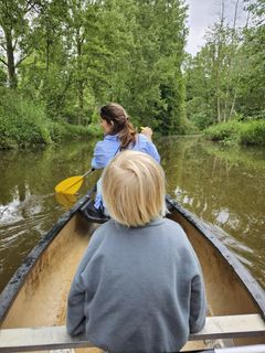 Een boot drijft op de rivier met een brug op de achtergrond.