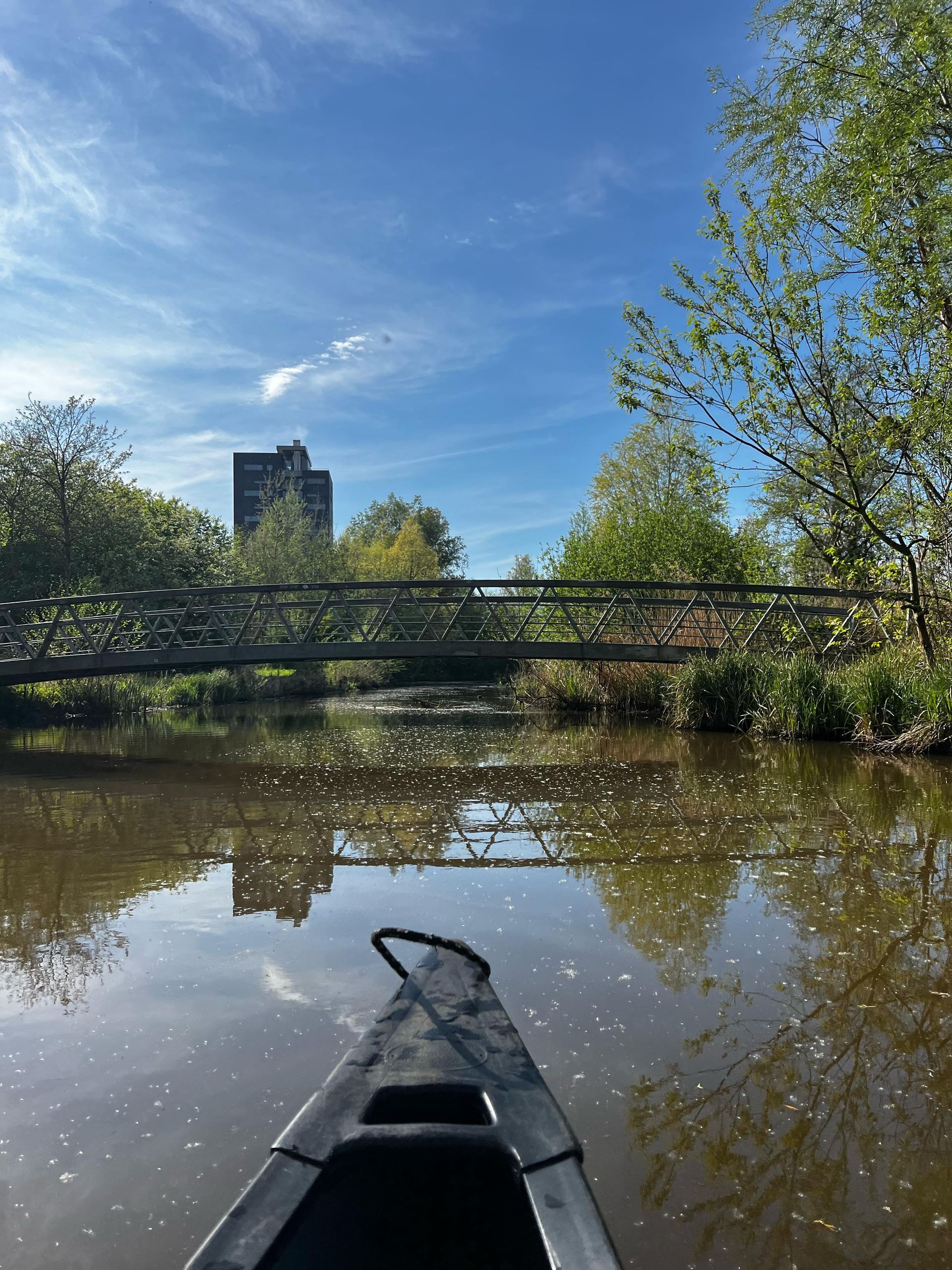 Een boot drijft op de rivier met een brug op de achtergrond.