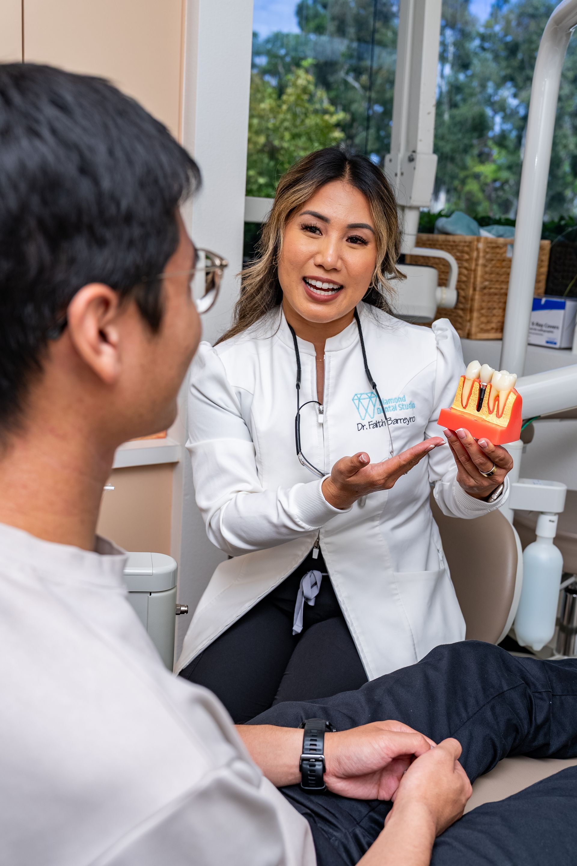Dentist explaining a model of teeth to a patient. Office setting.