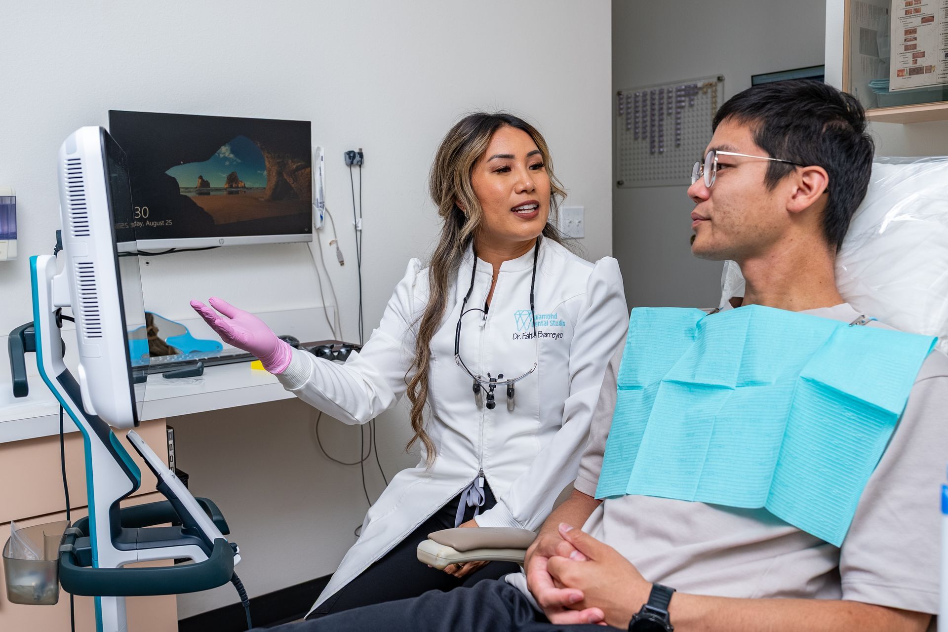 Dentist showing patient a screen in a dental office. Both are looking at the screen, smiling.