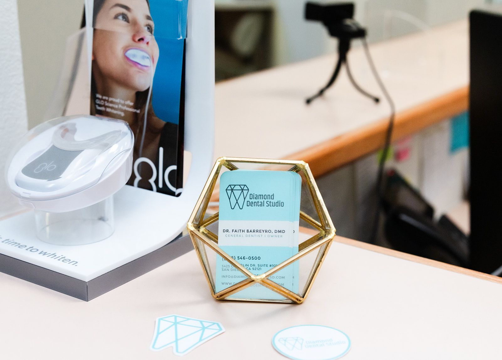 Reception desk with teeth whitening display, business cards, and a camera.