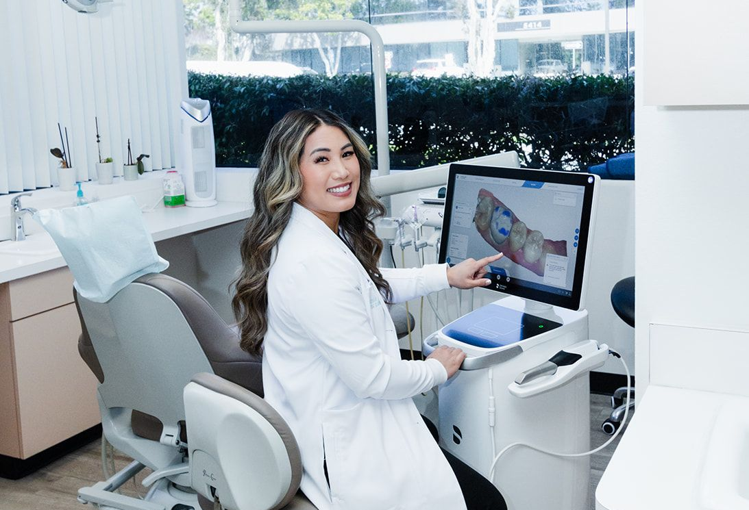 Woman dentist pointing to a 3D model on a computer screen in a dental office.