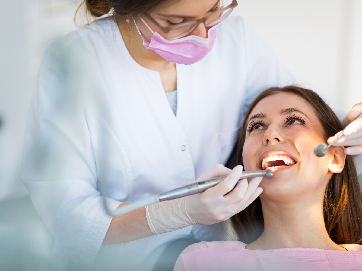 Dentist examining a patient's teeth with dental tools in a clinic.