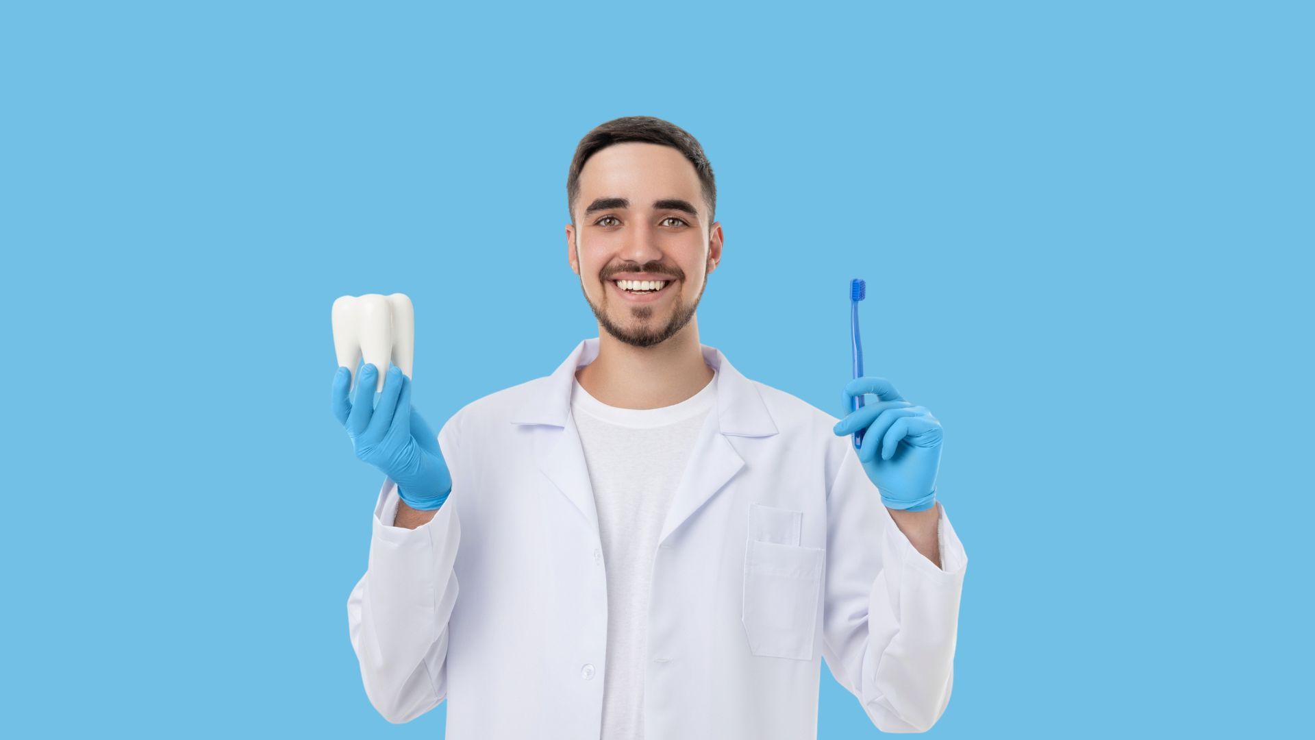 Dentist in white coat and blue gloves holding a toothbrush and dental tool against a blue background