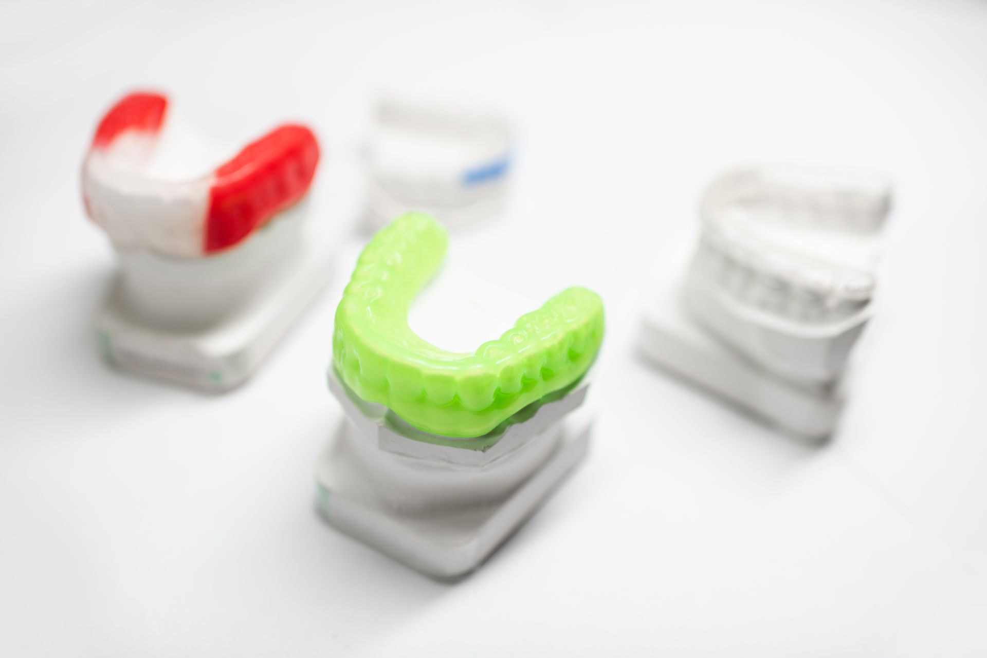 Dental molds with a green mouth guard, red, and white wax.
