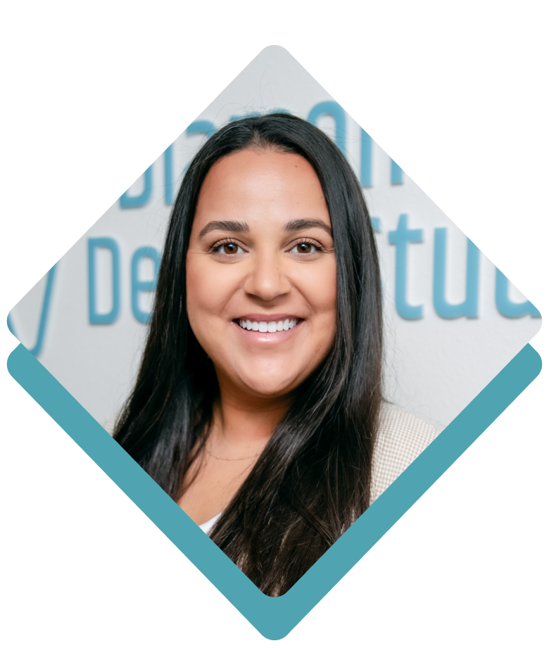 Smiling woman with long dark hair, wearing a white shirt; set in a teal diamond-shaped frame.