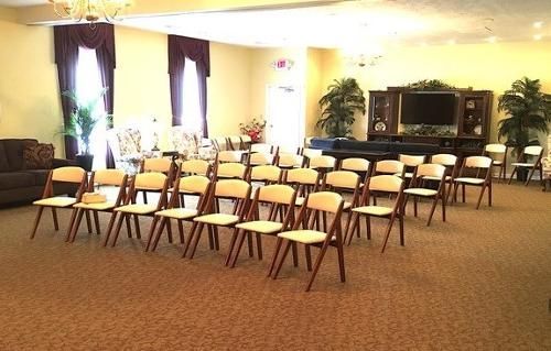 Empty room with rows of chairs facing a stage. Beige and brown tones.