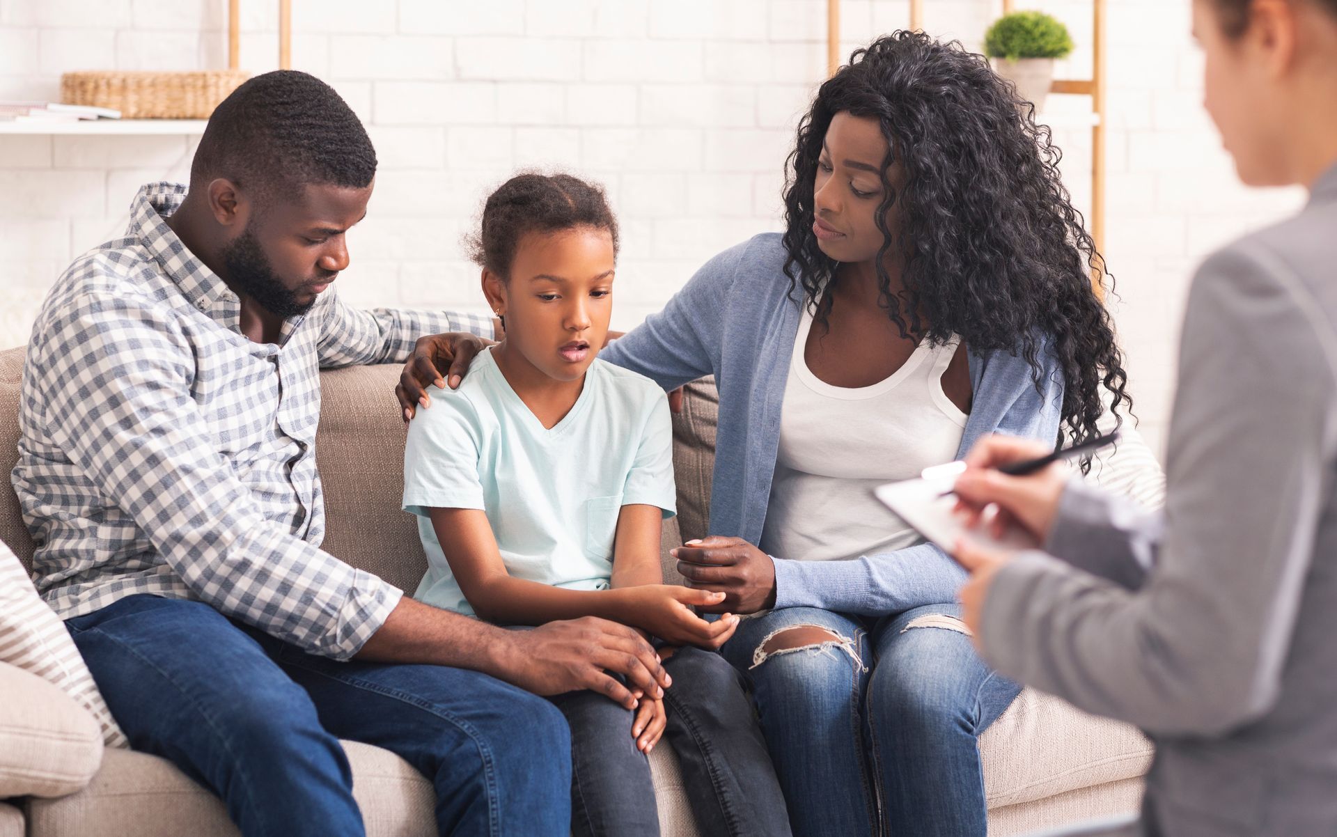 Family of three with a child talking to a therapist, indoors.