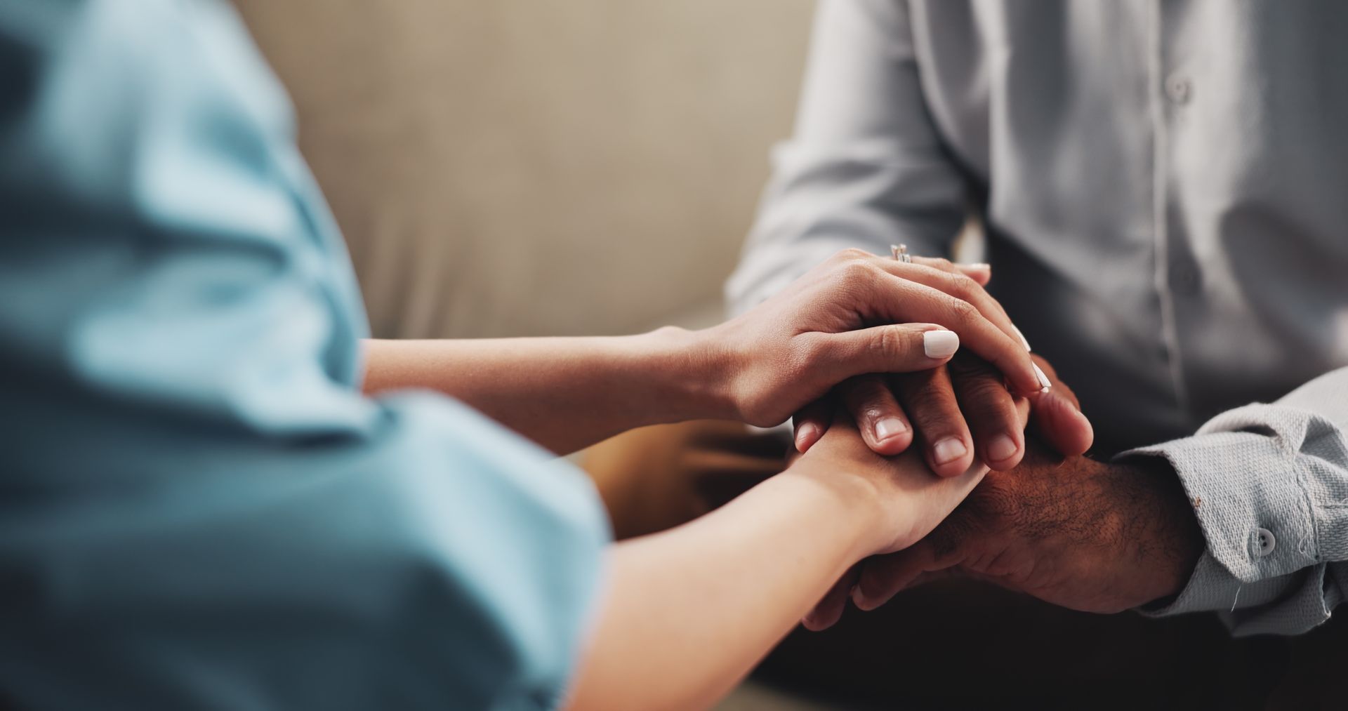 Two people hold hands, offering comfort and support.