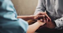 Two people hold hands, offering comfort and support.