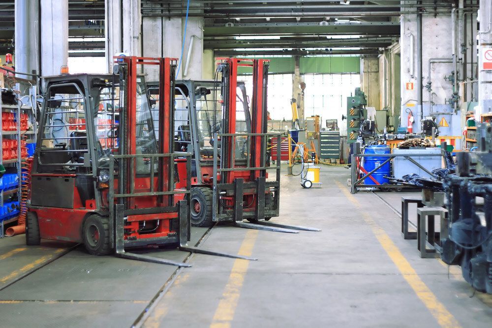 Three Red Forklifts Parked in a Factory Aisle— A1 Forklifts In Taree, NSW