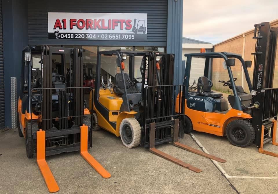 Three Orange Forklifts Parked in Front of a Building With — A1 Forklifts In South West Rocks, NSW