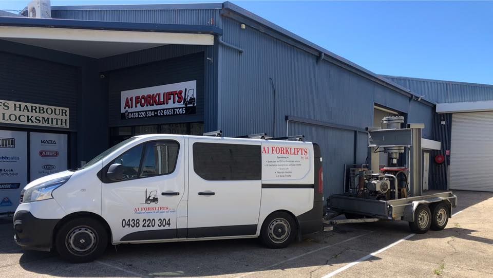 White Van Towing Machinery in Front of Building — A1 Forklifts In Nambucca Heads, NSW