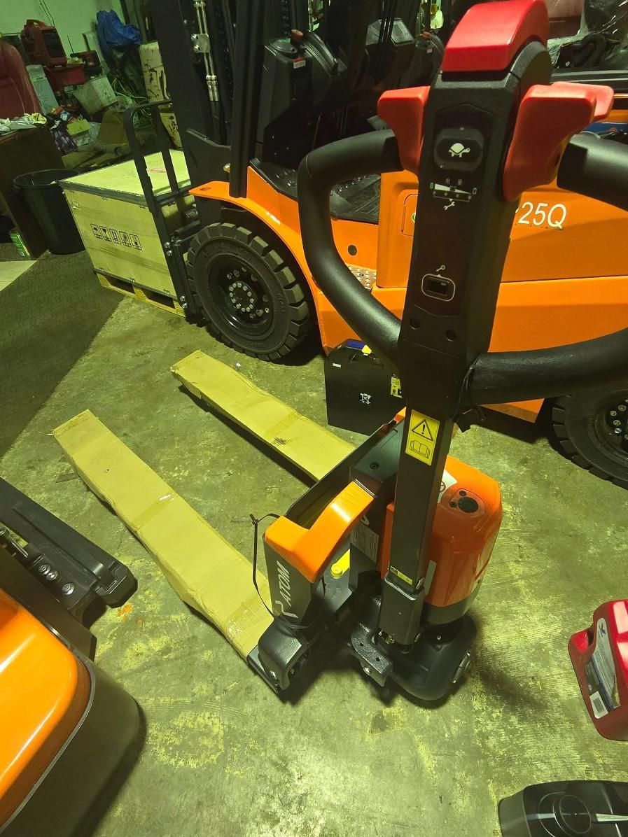 Orange Electric Pallet Jack With Forks, in a Warehouse Setting — A1 Forklifts In Taree, NSW