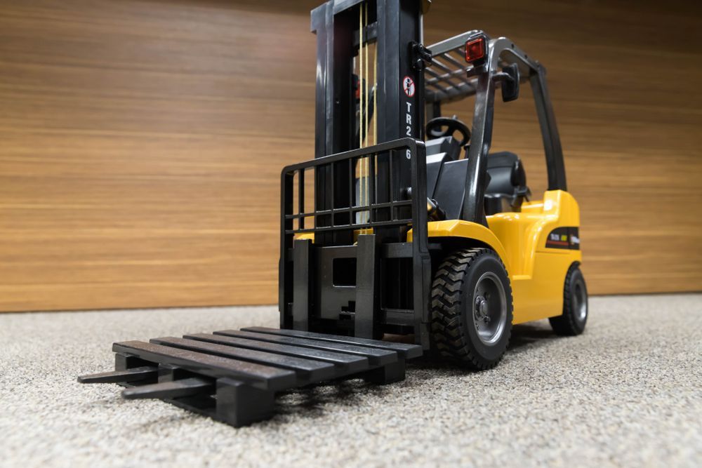 Yellow Forklift With a Black Pallet on a Carpeted Surface — A1 Forklifts In Kempsey, NSW