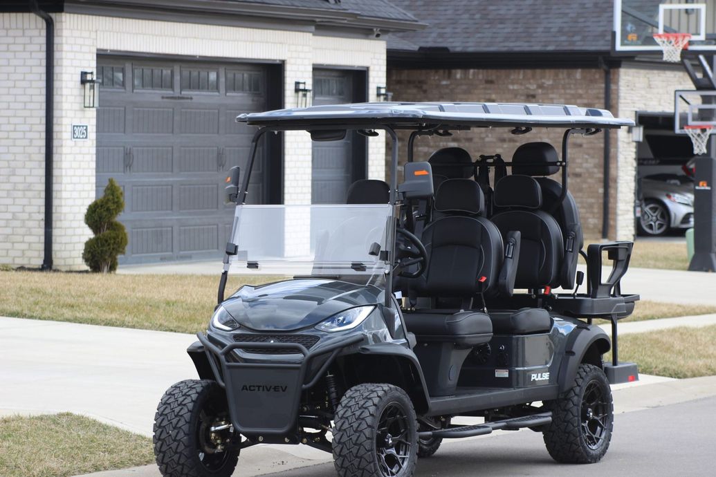 A golf cart is parked on the side of the road in front of a house.