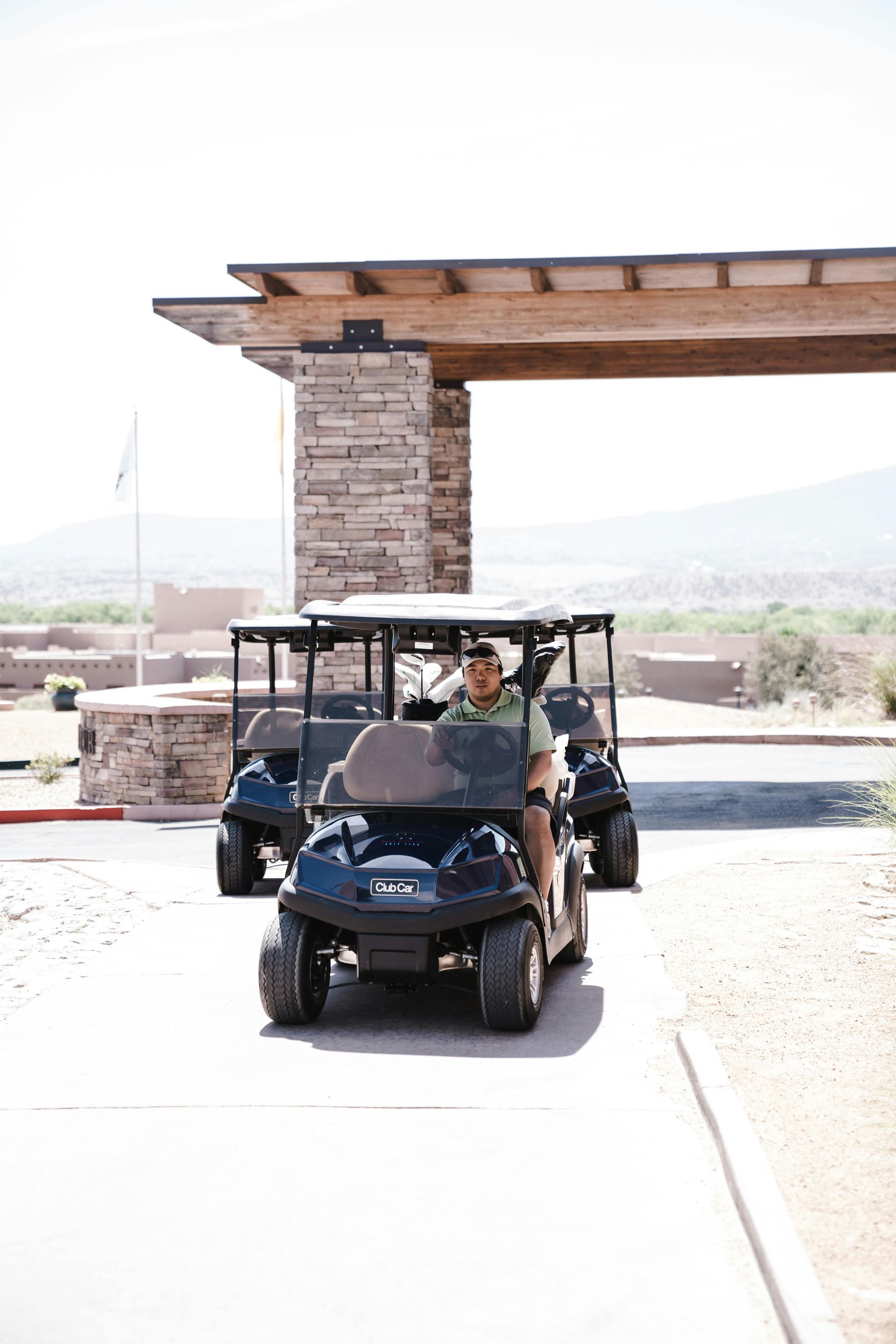 A man is driving a golf cart through a parking lot.