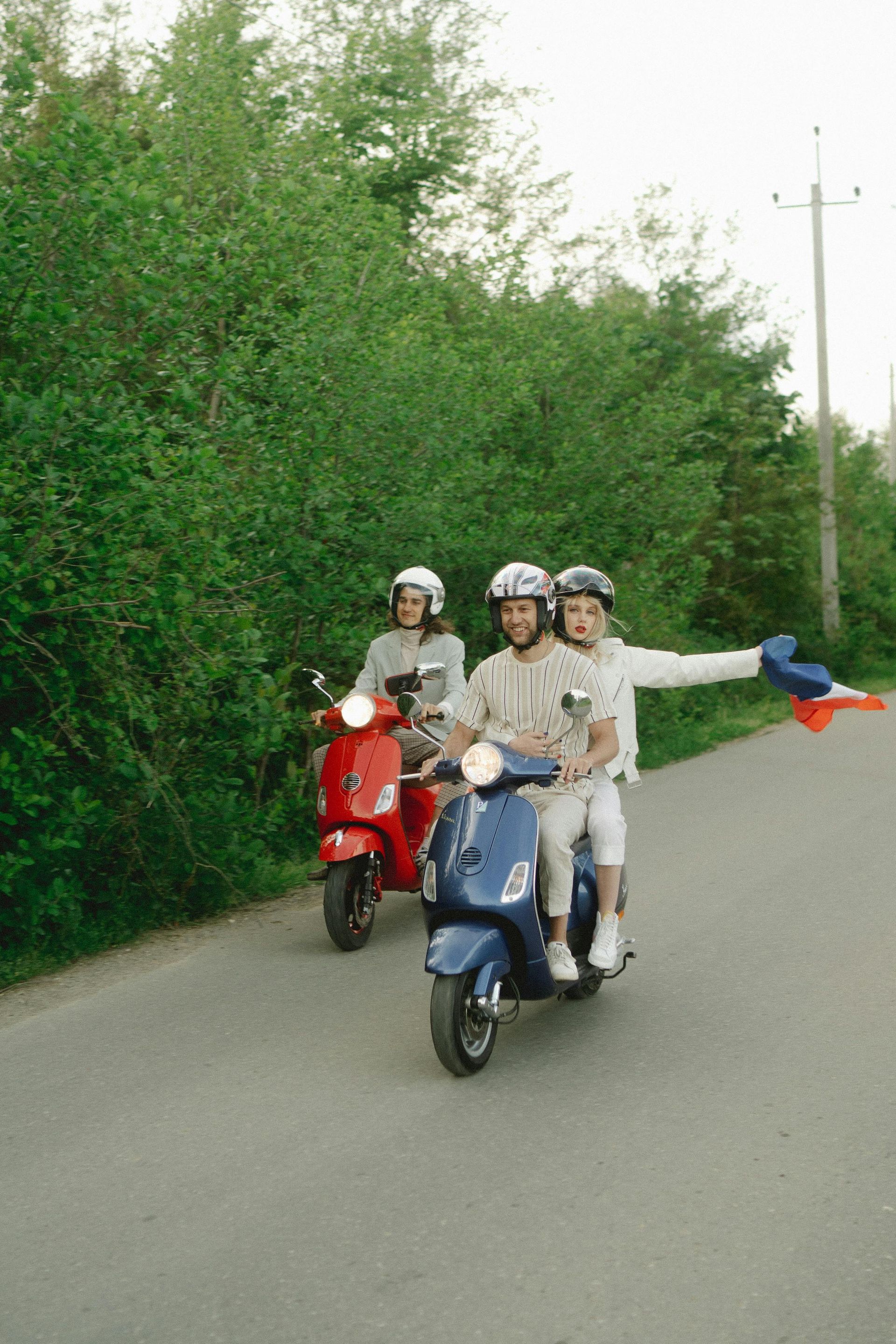 A group of people are riding scooters down a road.