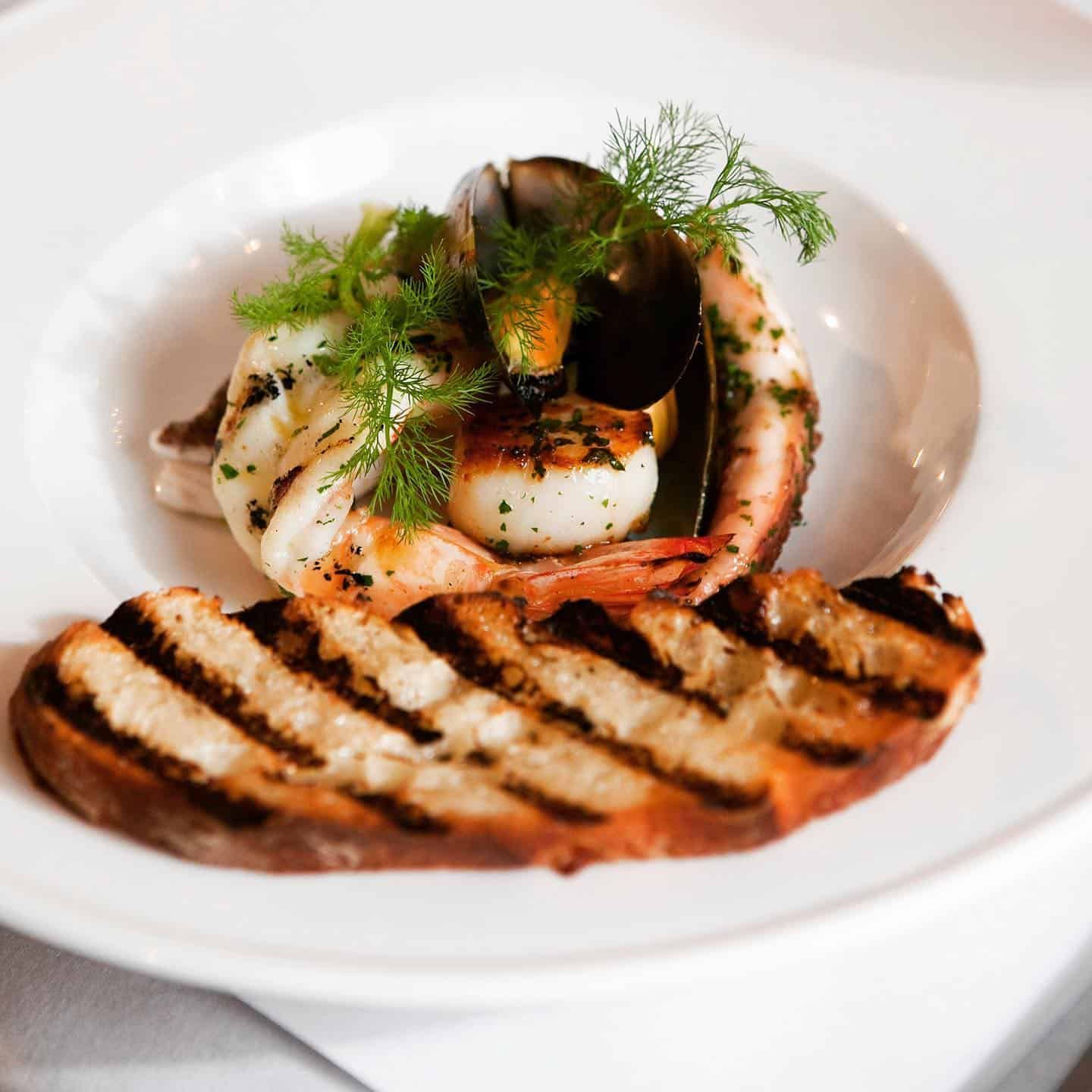 A White Plate Topped With Grilled Shrimp and Bread — Onesta Cucina in Bowral, NSW