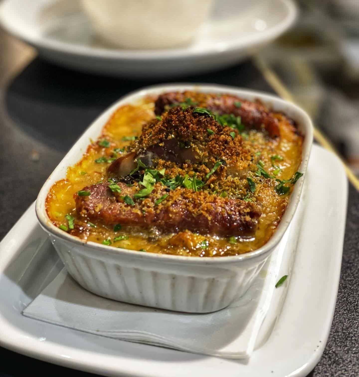 A Casserole Dish Filled With Meat and Vegetables is on a White Plate — Onesta Cucina in Bowral, NSW