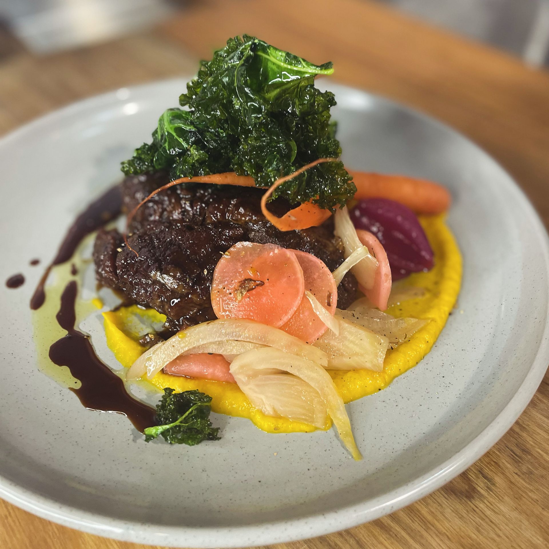 A plate with a yellow sauce, meat and vegetables — Onesta Cucina in Bowral, NSW