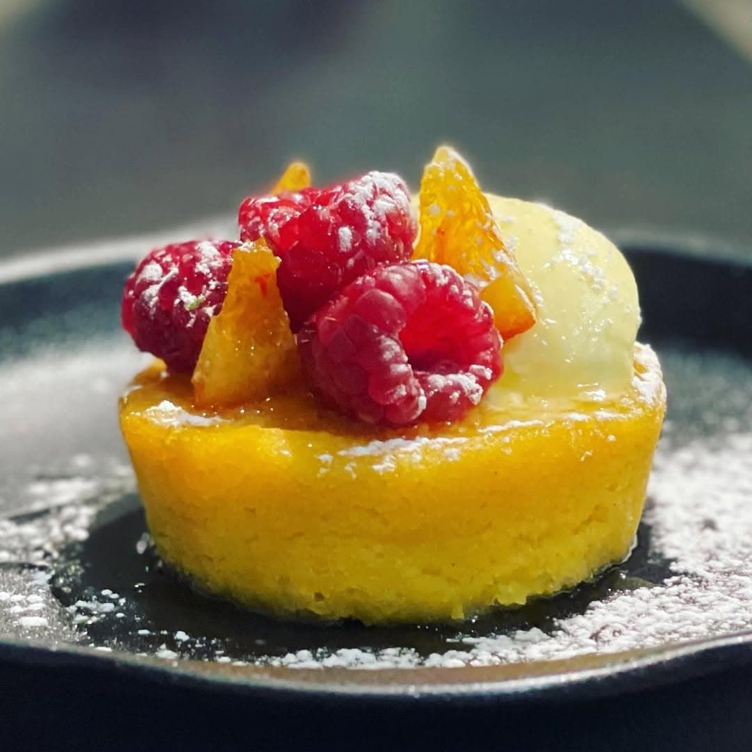 A Yellow Dessert With Raspberries and Orange Slices on Top — Onesta Cucina in Bowral, NSW