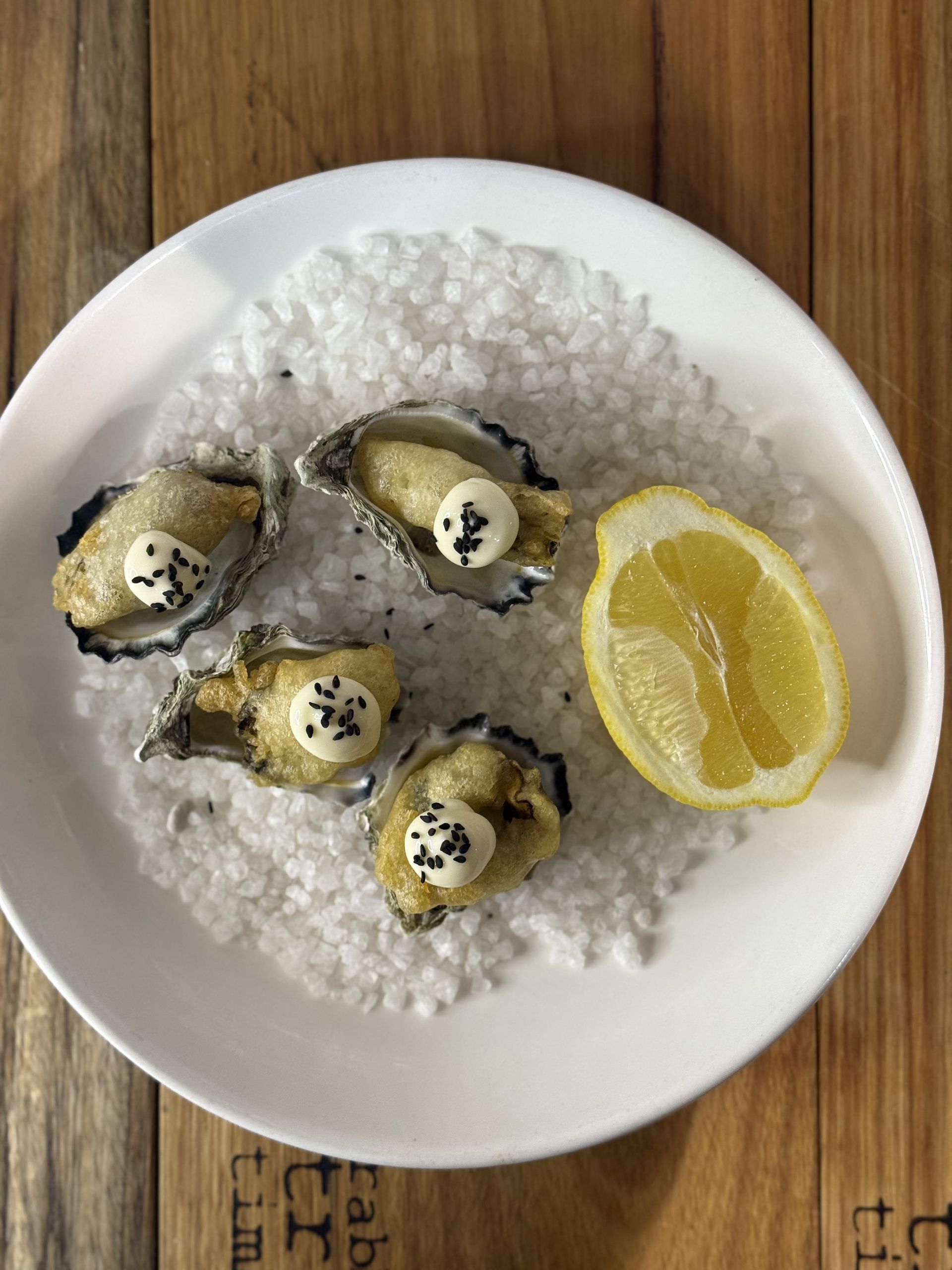 A white plate with salt, oysters and half a lemon — Onesta Cucina in Bowral, NSW